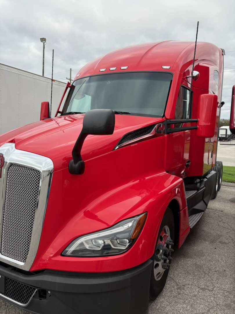 Kenworth T680 tow red truck in profile view showing front grille, headlights, and side mirror.