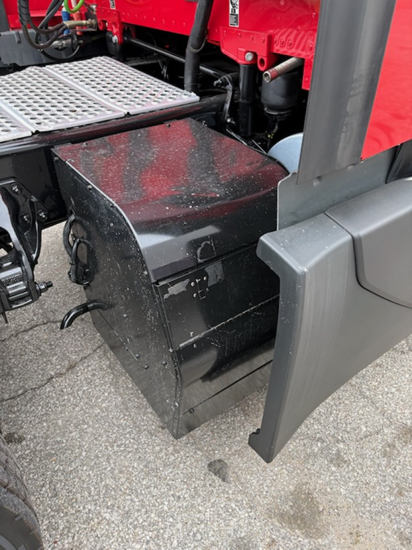 Engine bay area showing black rectangular toolbox or battery box mounted near the frame of a 2023 Kenworth T680 tractor unit with red body; steps and wiring visible.