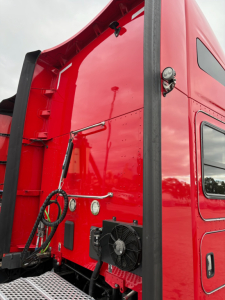 Kenworth T680 truck sleeper cab exterior showing red paint, rear access area with exterior radiator and cooling fan, ladder area, and window. Includes VIN/sticker area hints.