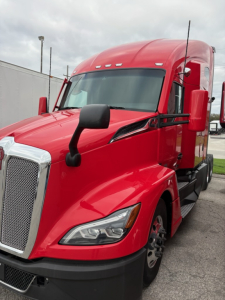 Kenworth T680 tow red truck in profile view showing front grille, headlights, and side mirror.