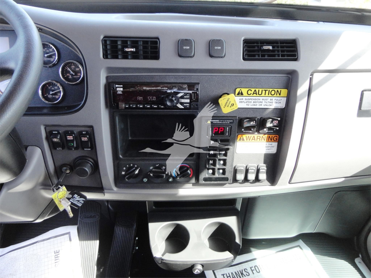 Peterbilt 337 dashboard/center console with cruisem control and gauges, warning labels and cup holders.
