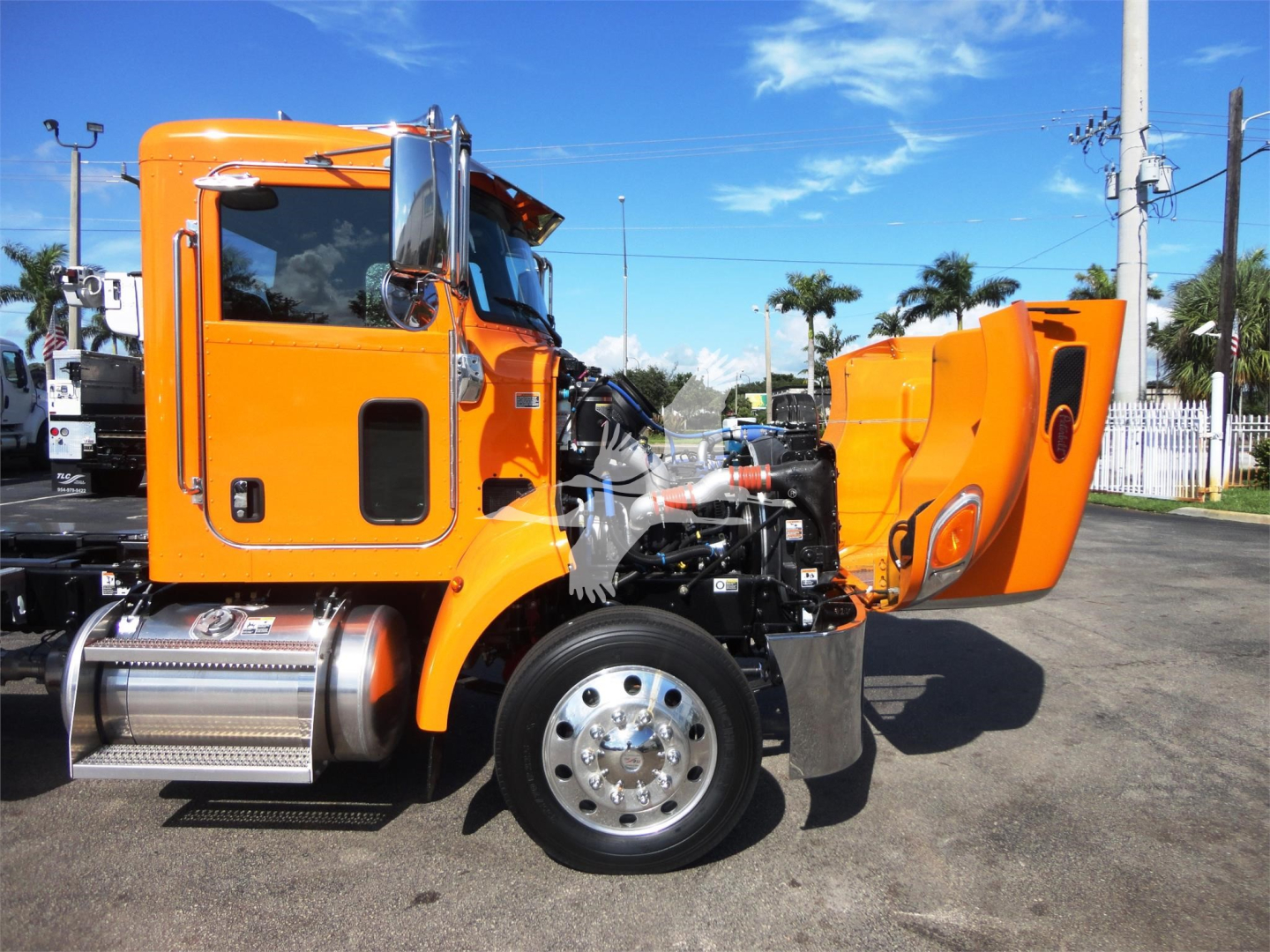 Peterbilt 337 truck in orange with hood open showing engine bay and side steps.