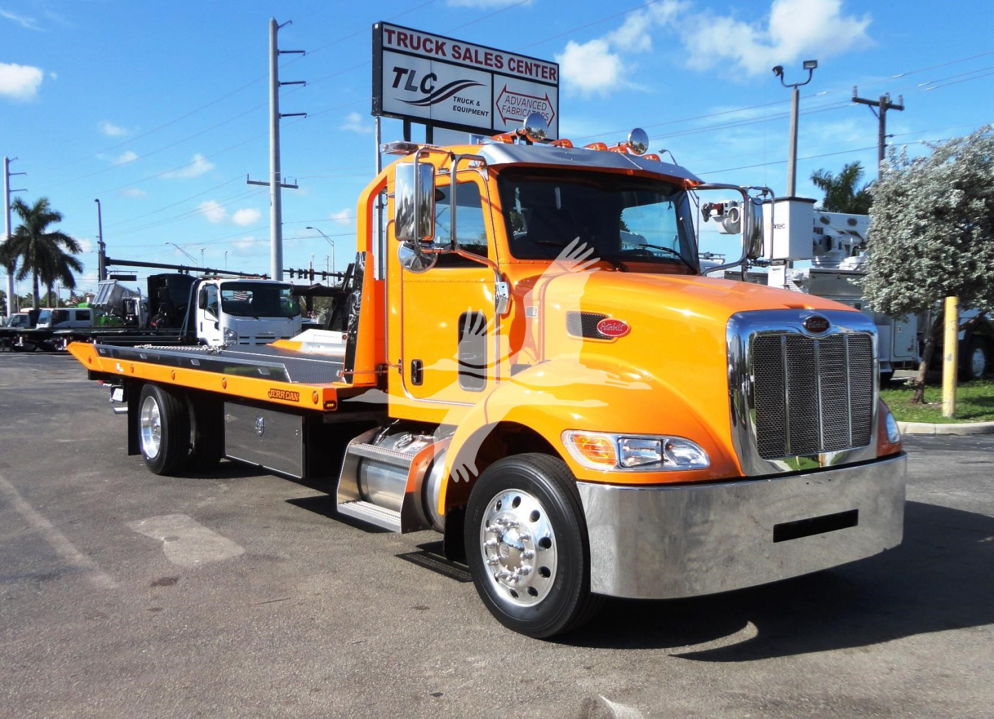 Tow truck (Peterbilt 337) orange rollback with flatbed, front grille, chrome bumper, and side mirrors visible.