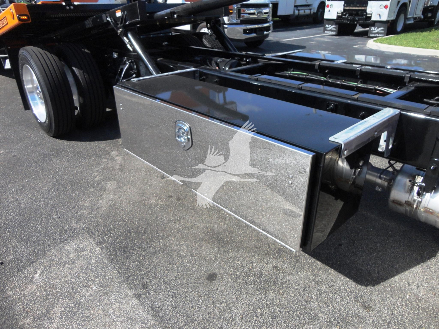 Truck undercarriage with polished aluminum toolbox mounted on frame, Peterbilt 337 rollback chassis visible, chrome components and tires.
