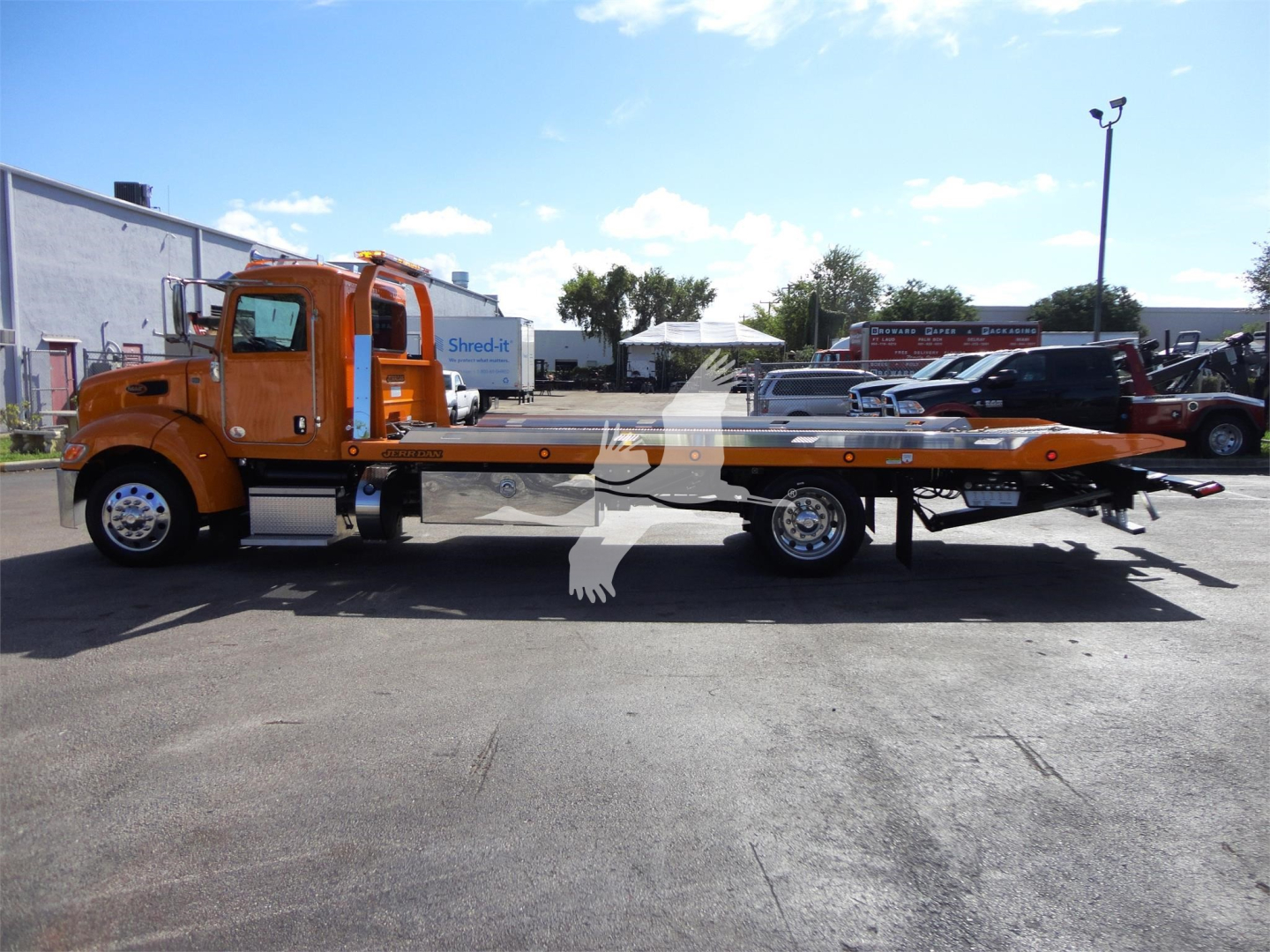 Truck cab with flatbed rollback tow truck, orange color, side view showing long flatbed with winch and lights, Peterbilt 337 model.