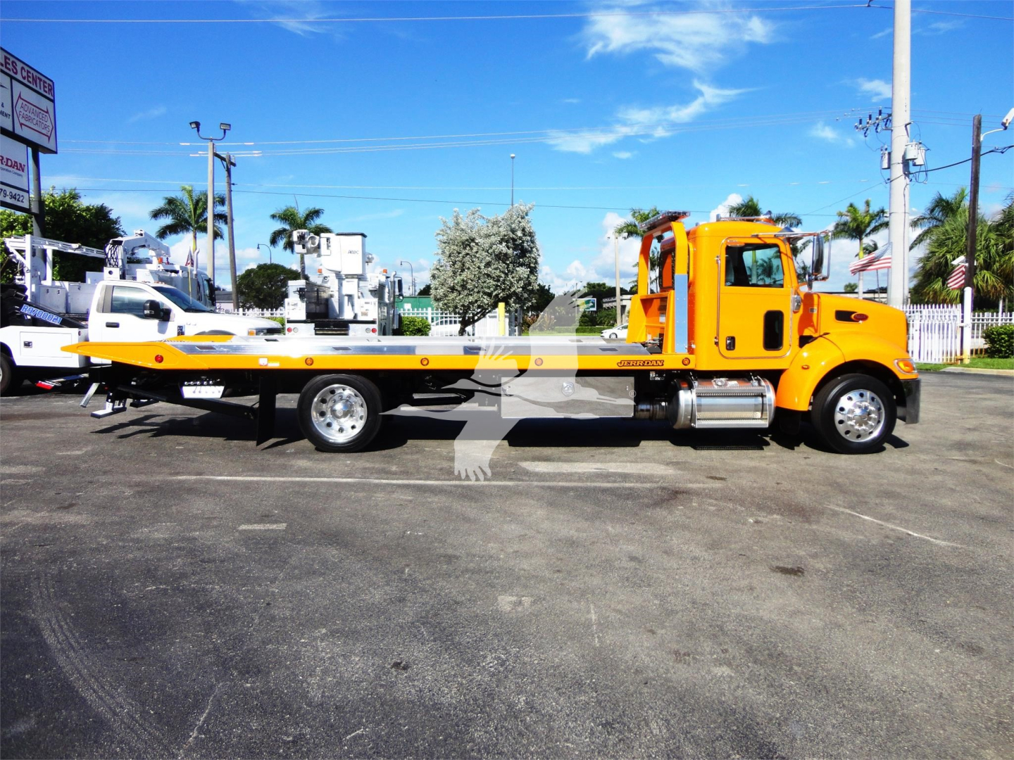 Peterbilt 337 rollback tow truck side view showing long flatbed with bright yellow cab and wheel, chrome exhaust, and lettering along bed