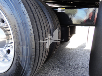 Truck rear wheels of a 2022 Peterbilt 337 rollback showing dual tires and undercarriage with a reflection on the shiny frame.