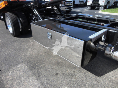 Truck undercarriage with polished aluminum toolbox mounted on frame, Peterbilt 337 rollback chassis visible, chrome components and tires.