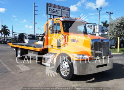 Peterbilt 337 rollback tow truck in orange with flatbed, front grille, chrome bumper; truck yard background with sign TL C Truck Sales Center. Visible text includes TLC Truck Sales Center watermark and stock info overlay.