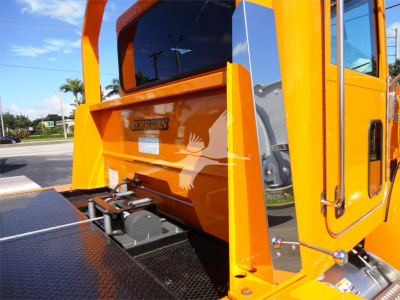 Peterbilt 337 rollback truck rear with metallic diamond plate platform and bright orange body, showing rear window and tail area.