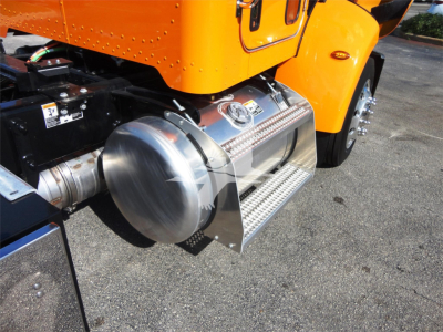 Peterbilt 337 side view showing chrome fuel tank guard and side step on orange truck, portion of rear wheel and chassis visible.