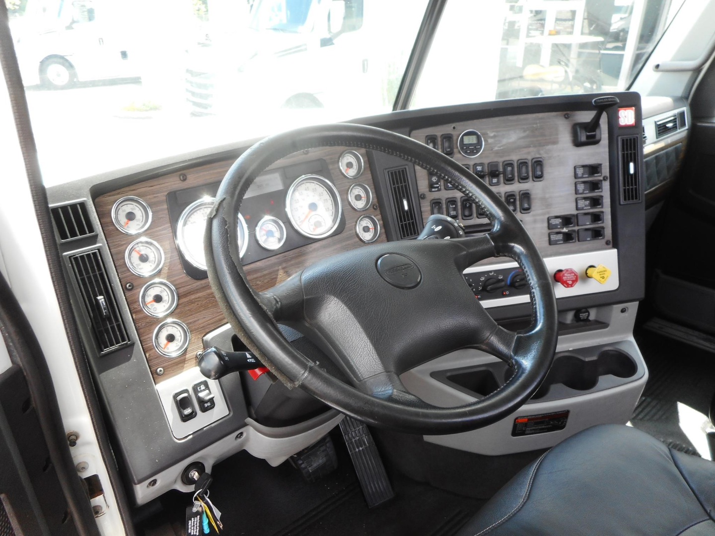 Interior of a Freightliner 122SD truck cab showing steering wheel, dashboard with multiple gauges, switches, and controls.