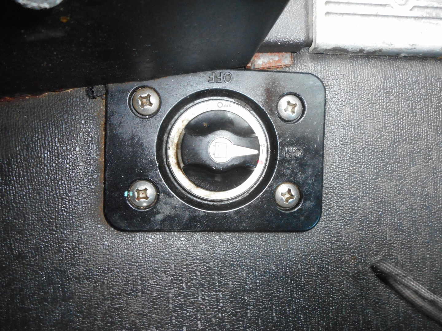 Truck interior/cab floor showing a circular latch/lock with four screws, labeled KEY and OFF around the circle, on a black plate.