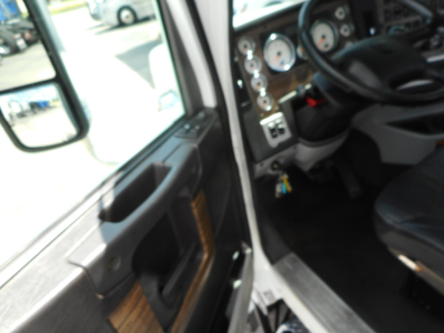Truck cab interior with steering wheel and instrument cluster visible through open door.