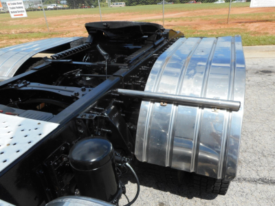 Truck chassis frame and rear fender area with shiny metal fuel tanks and black components visible; some tubing and mounts; no legible text visible.