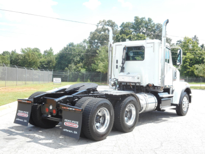 Tractor unit with white cab and chrome exhaust stacks, three rear axles, showing fifth wheel and rear tires; Freightliner 122SD cab with long hood.