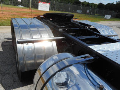 Semi truck chassis with polished aluminum fuel tanks and rear cab area, Freightliner 122SD, chrome tank guards, chassis rails, and fifth wheel area visible.