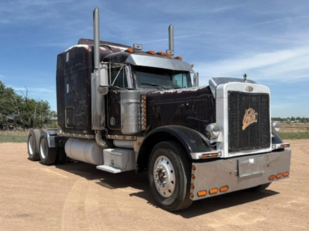 Peterbilt 379 UltraCab extended hood semi-truck, black with chrome accents, dual stacks, large front grille, daytime running lights, white bumper and side mirrors visible.