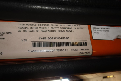 Vehicle VIN sticker on orange truck shows VIN 4V4M19DG3CN548340 and text: THIS VEHICLE CONFORMS TO ALL APPLICABLE U.S.A. FEDERAL MOTOR VEHICLE SAFETY STANDARDS IN EFFECT ON THE DATE OF MANUFACTURE SHOWN ABOVE. VIN 4V4M19DG3CN548340 CLASSIFI