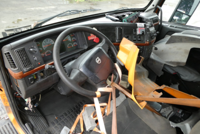 Volvo VNM42T truck interior view showing steering wheel dash and dashboard instruments with orange seat belt covers and control panels.