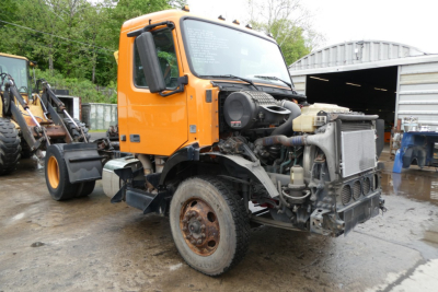 Truck cab front with exposed engine bay on a Volvo VNM42T conventional daycab showing radiator and engine components