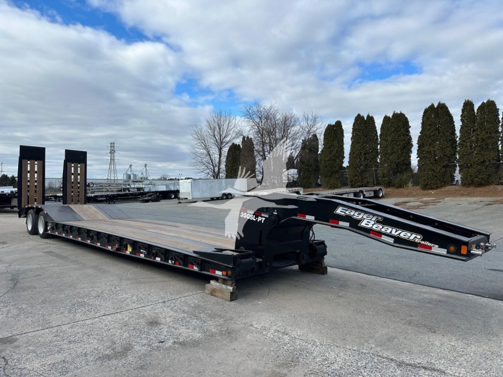 Lowboy trailer showing dual ramps and extended flatbed with 'Eager Beaver' branding and black/gray color.”