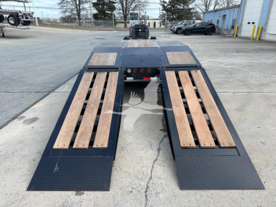 Lowboy trailer with fold-out ramps showing wooden boards on each side and a black steel deck.