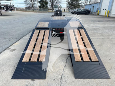 Lowboy trailer rear view showing dual loading ramps with wooden planks and diamond plate deck, blue/black metal surfaces.