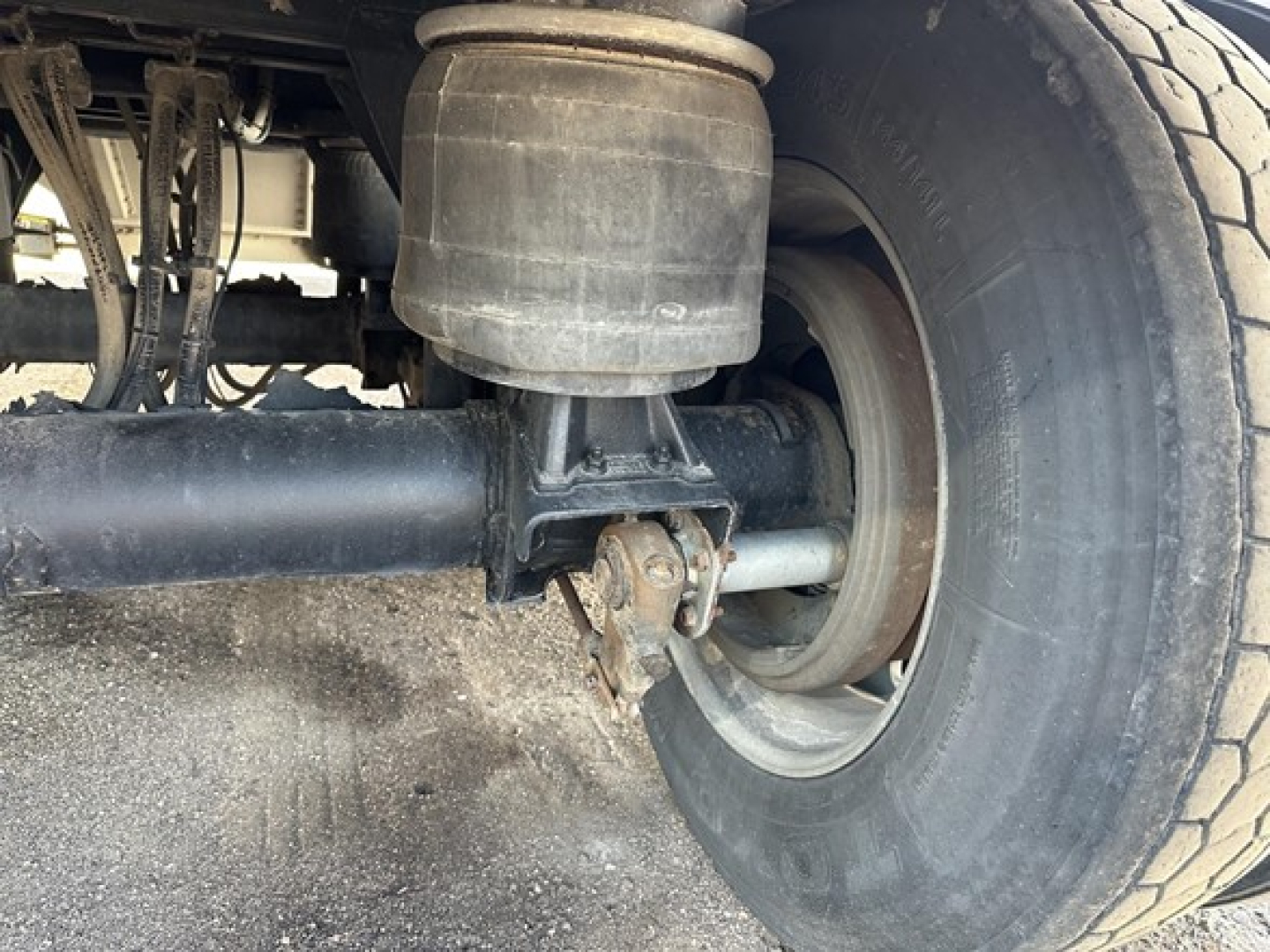 Suspension and rear wheel area of a Merritt Heritage trailer showing air suspension bag, axle, leaf spring, and tire.
