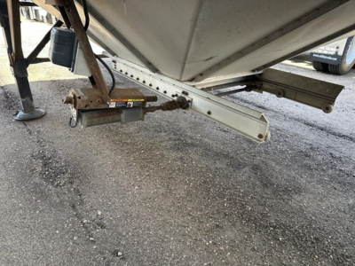 Trailer hitch area of a Merritt Heritage hopper trailer showing the underside frame, tongue with coupler, and hydraulic jack assembly.