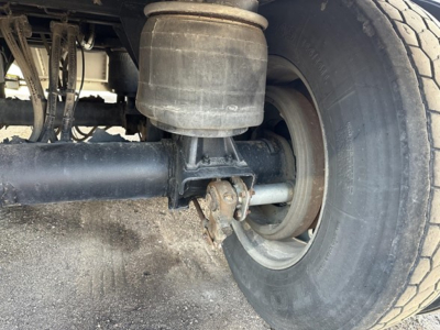 Suspension and rear wheel area of a Merritt Heritage trailer showing air suspension bag, axle, leaf spring, and tire.