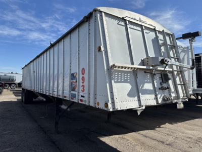 Trailer side and rear of a 2015 Merritt Heritage hopper trailer showing metal panels, hinged tailgate, support legs, and hitch point with reflective markers.