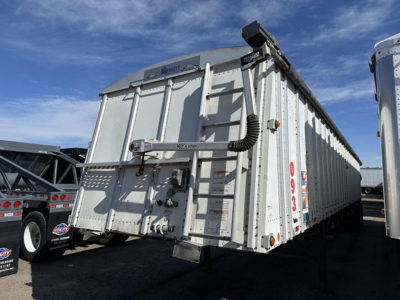Trailer side and rear showing Merritt brand hopper trailer, with identification numbers and hydraulic hoses; visible text includes Merritt brand name and model elements.