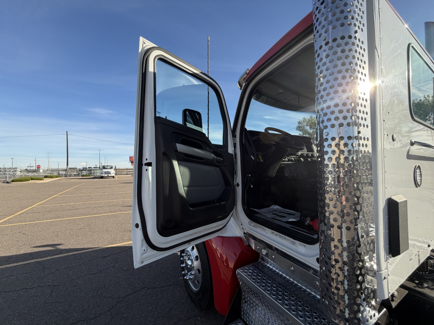 Kenworth T880 cab exterior with driver door open showing interior and chrome side steps.