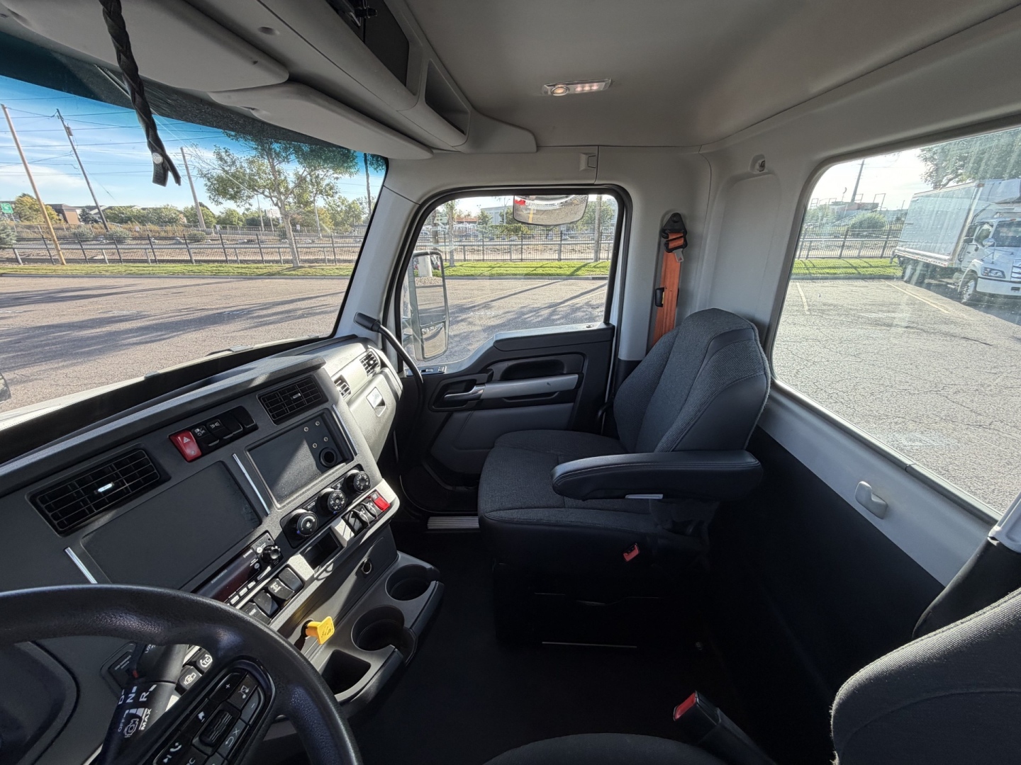 Kenworth T880 cab interior showing driver seat and dashboard with steering wheel, control switches, and center console.