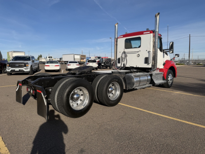 Kenworth T880 conventional daycab truck chassis with dual rear axles and red cab, side view showing fuel tanks, exhaust stacks, and hitch.