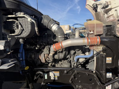 Kenworth T880 engine bay showing intake hoses, radiator, and various fluid reservoirs in view.