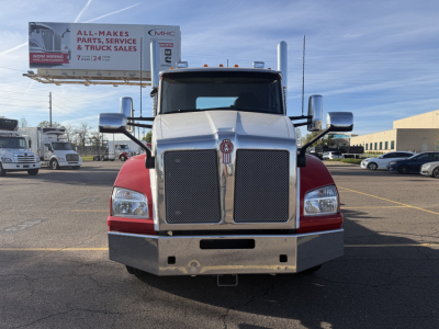 Kenworth T880 front view showing large chrome grille, dual headlights, red fenders, and heavy-duty bumper in a truck lot.