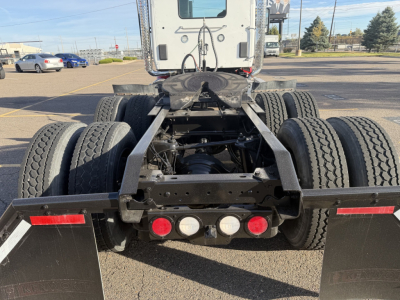 Kenworth T880 chassis rear view showing fifth wheel, dual rear axles, and mud flaps with red reflectors.