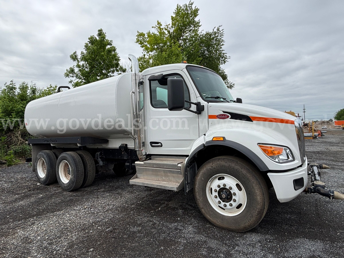 Peterbilt water truck cabin and 4000 gallon tank mounted on tractor-trailer chassis with front wheel, water tank, and ladder; no visible text on side.