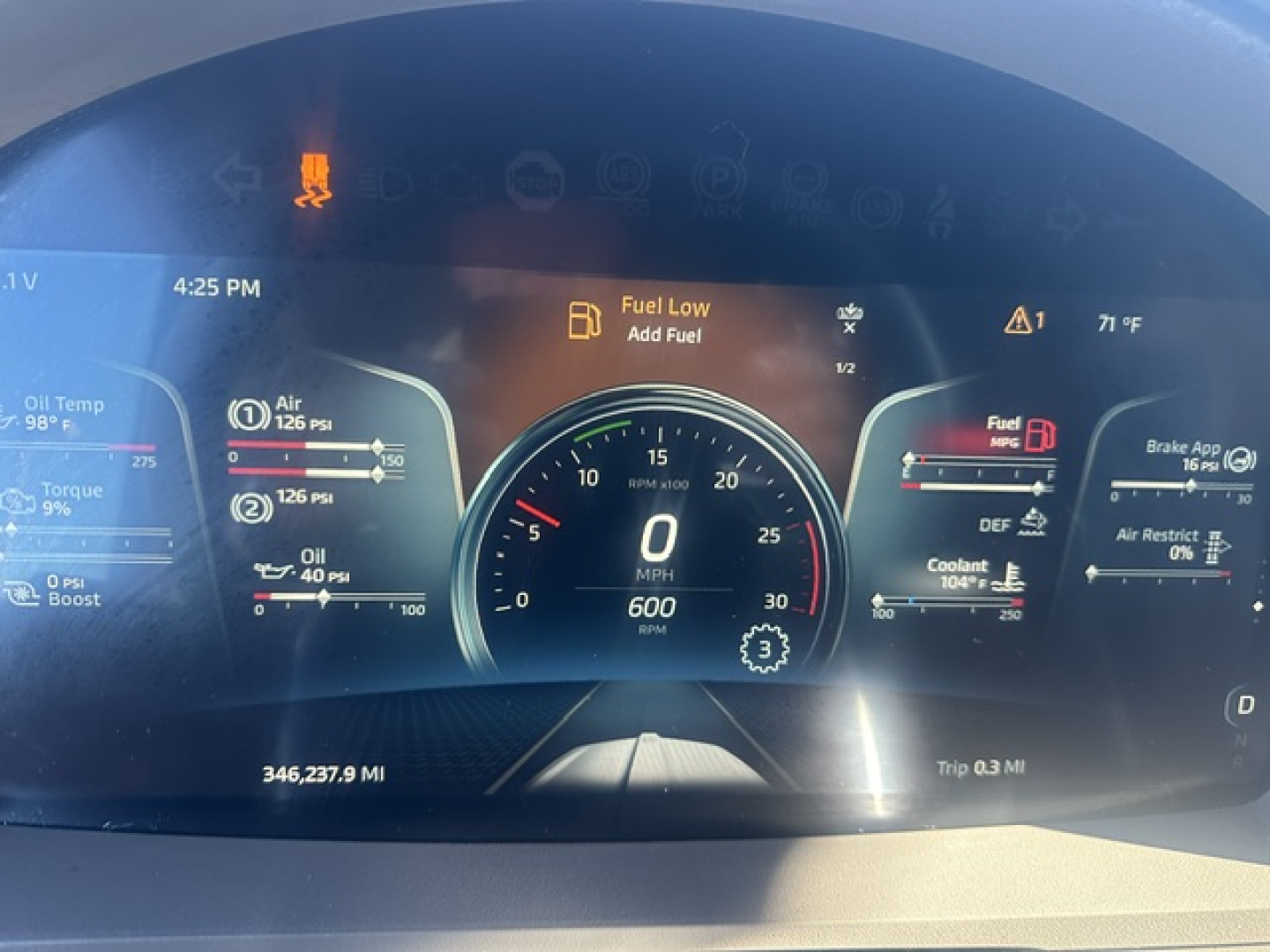 Kenworth T680 digital instrument cluster display showing fuel low alert, speedometer at 0, trip data, and engine gauges.