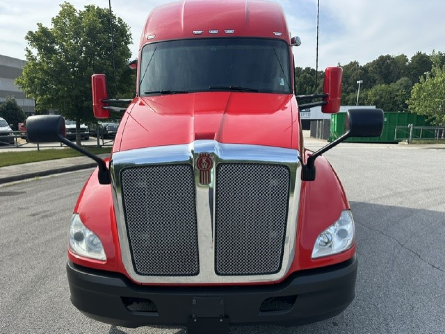 Front view of a red Kenworth T680 sleeper cab truck showing large chrome grille, headlights, and side mirrors.