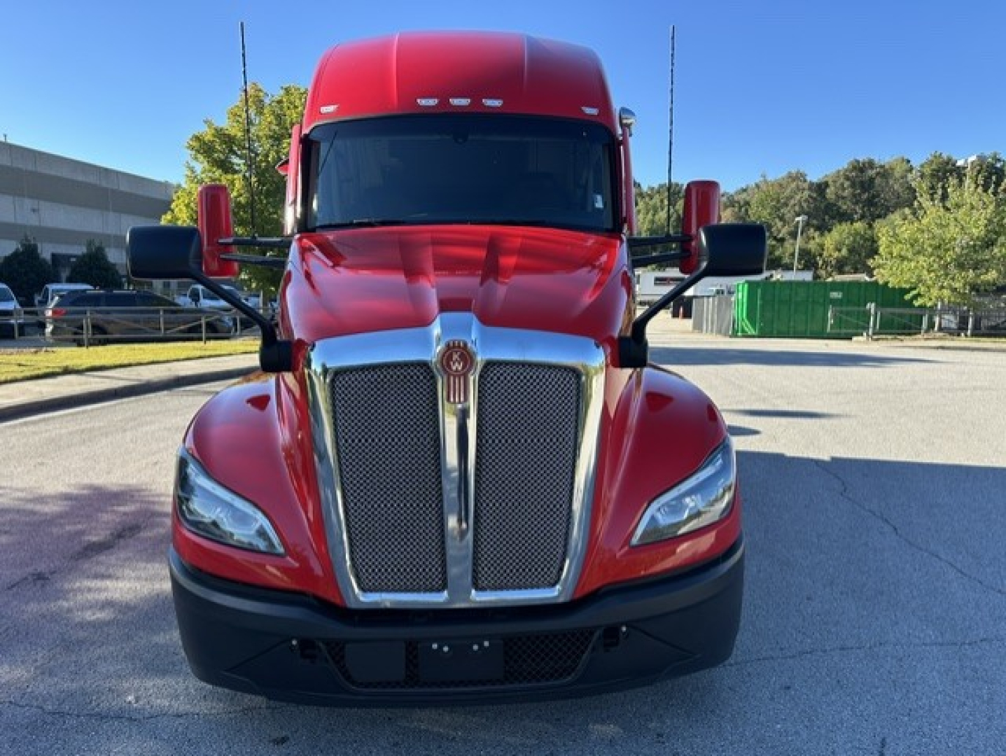 Kenworth T680 front view showing bold chrome grille, red cab, and black bumper.