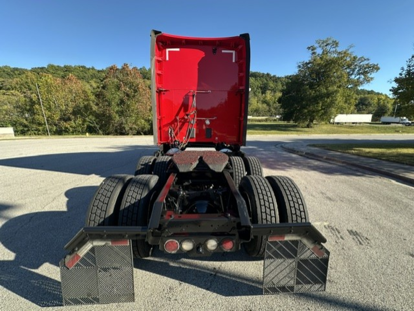 Kenworth T680 rear view showing fifth wheel and dual fuel tanks under red cab, no trailer attached.