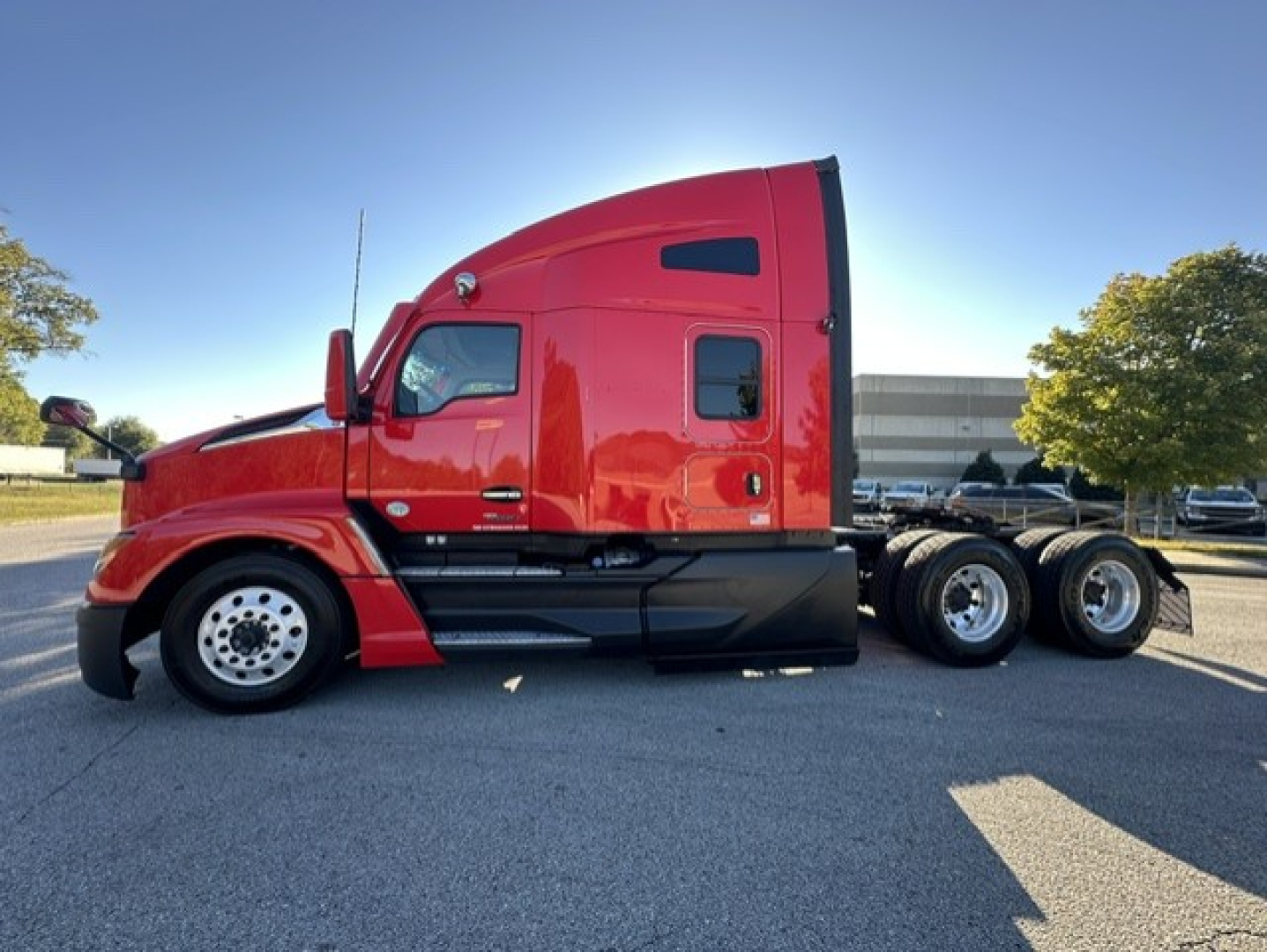 Kenworth T680 conventional sleeper truck side view showing red exterior and dual rear axles.
