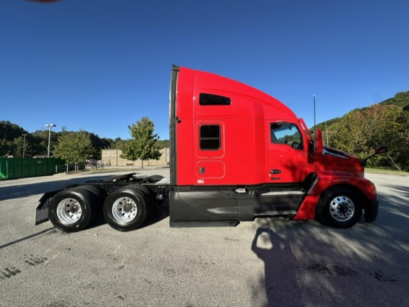 Kenworth T680 sleeper cab chassis side view showing red exterior and dual rear axles.