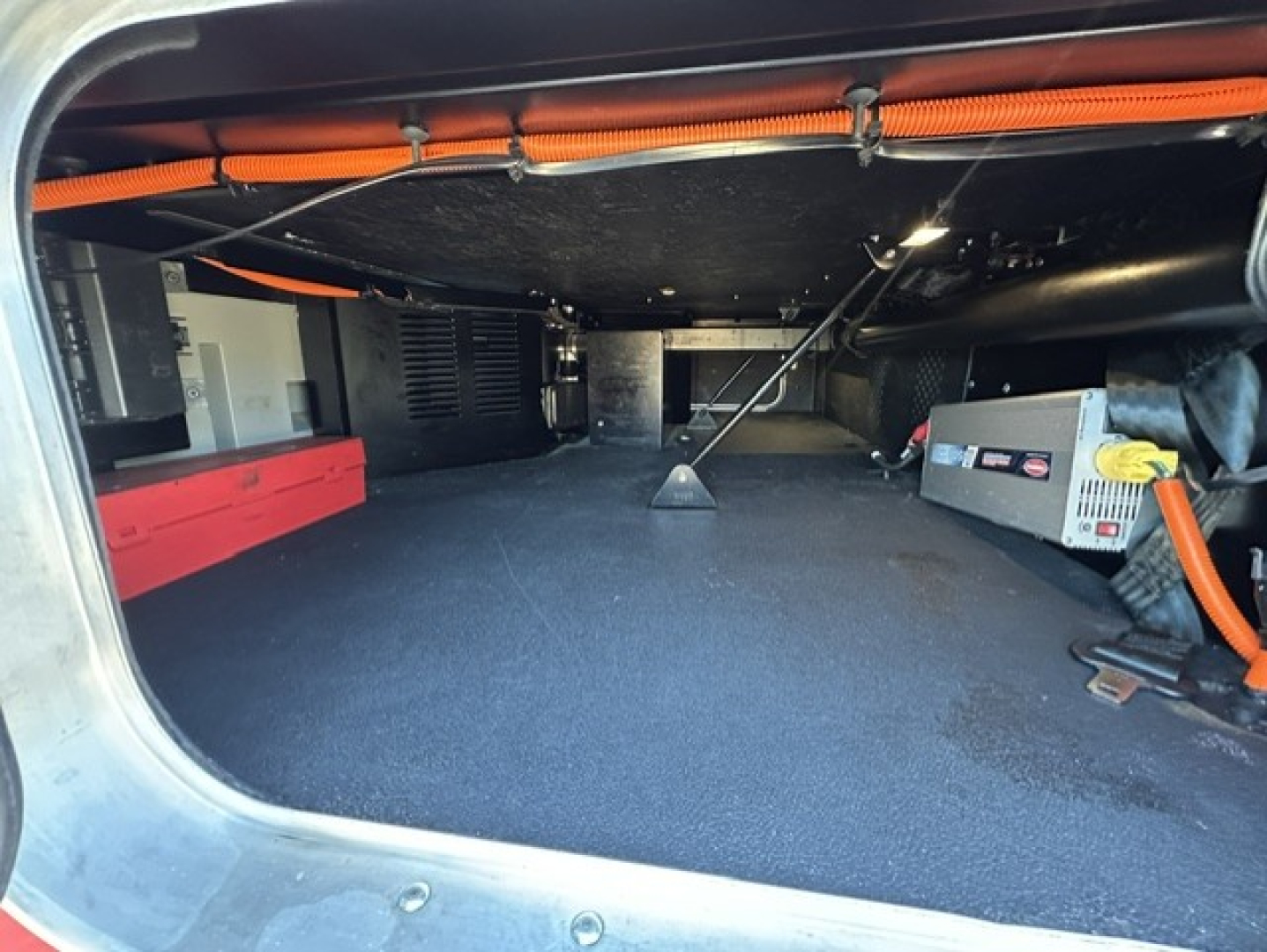 Kenworth T680 cargo area showing clean, carpeted storage with orange cables and equipment on right side.