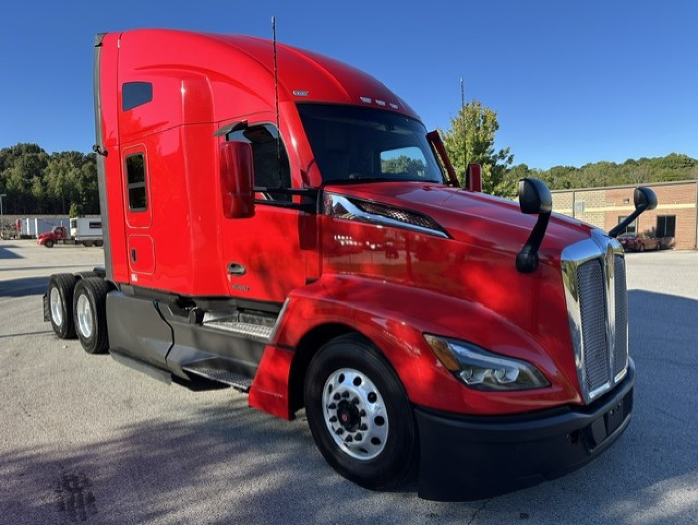 Kenworth T680 truck in red, front three-quarter view showing aerodynamic hood, chrome grille, black bumper, side mirrors, and dual rear axles.