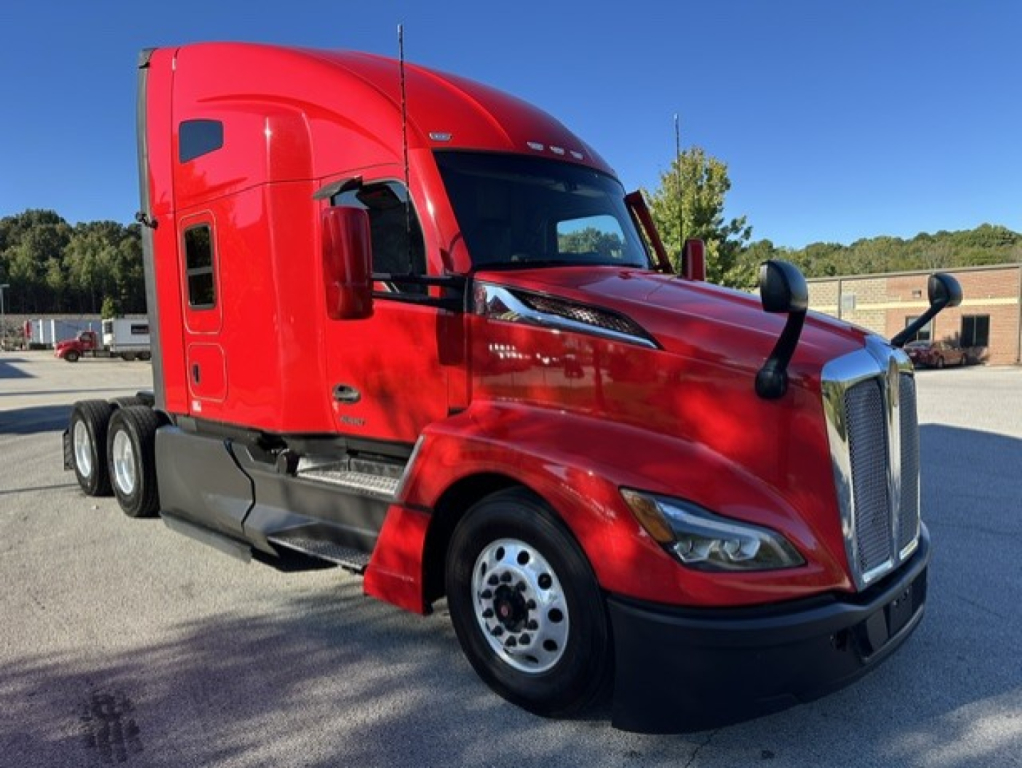 Kenworth T680 truck in red, front three-quarter view showing aerodynamic hood, chrome grille, black bumper, side mirrors, and dual rear axles.