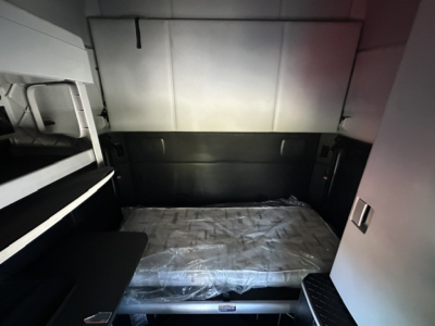 Kenworth T680 cab interior bunk area with mattress in plastic wrap and side storage compartments visible.